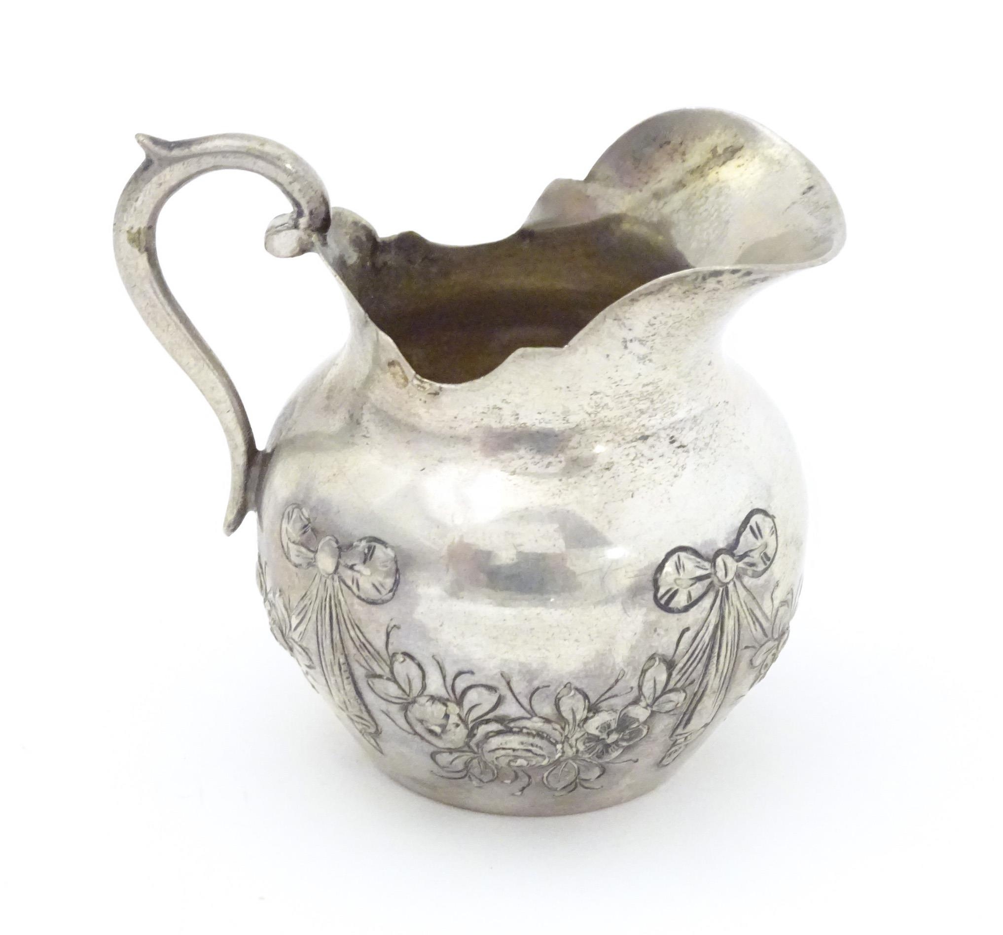 A small Continental .800 silver cream jug with ribbon and swag decoration. Marked under possibly