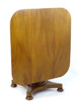 A Victorian mahogany tilt top table with rounded edges and standing on a pedestal base with