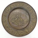 A large 20thC Continental embossed brass charger decorated with a bucolic central scene with figures