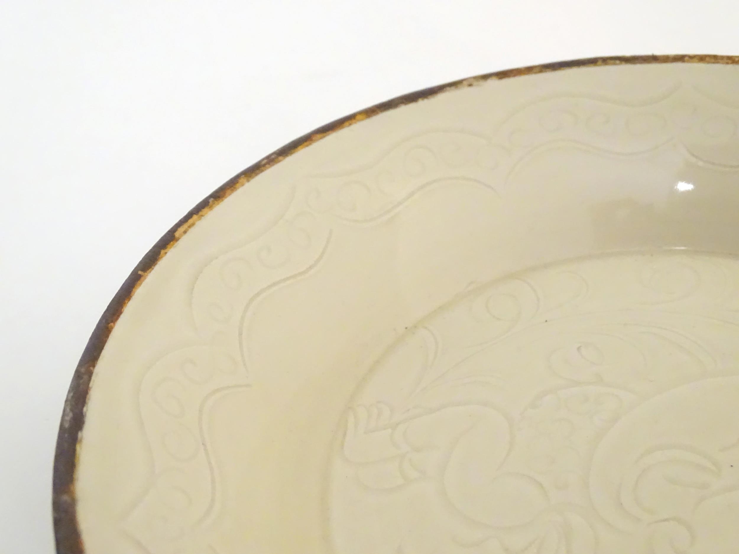 A Chinese Ding style dished plate with relief decoration depicting a stylised baby. Approx. 8" - Image 4 of 6