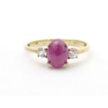 A 9ct gold ring with ruby coloured cabochon flanked by two white stones. Ring size approx. N 1/2