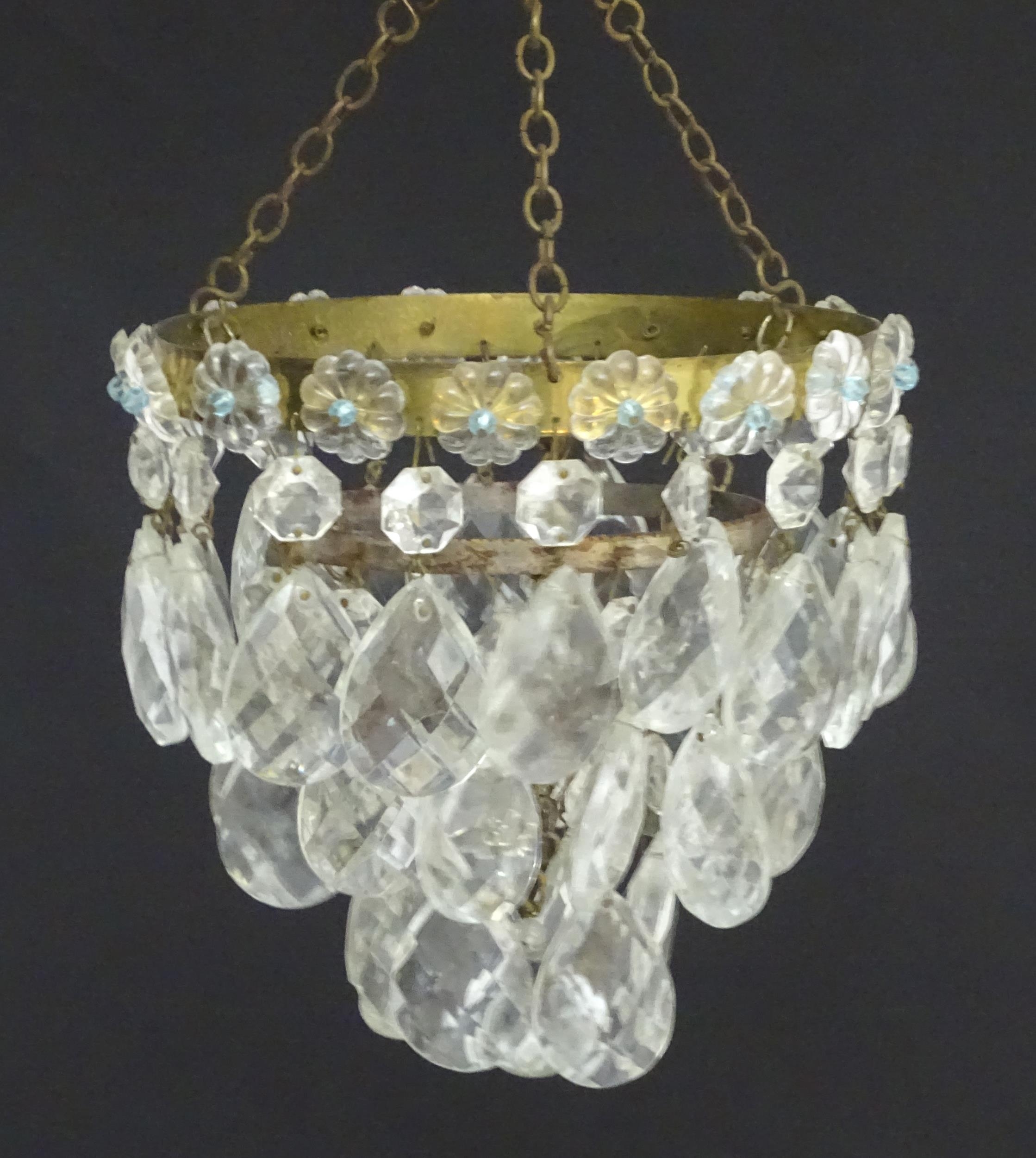 An early 20thC crystal drop bag pendant chandelier, the circular gilt metal mounts supporting