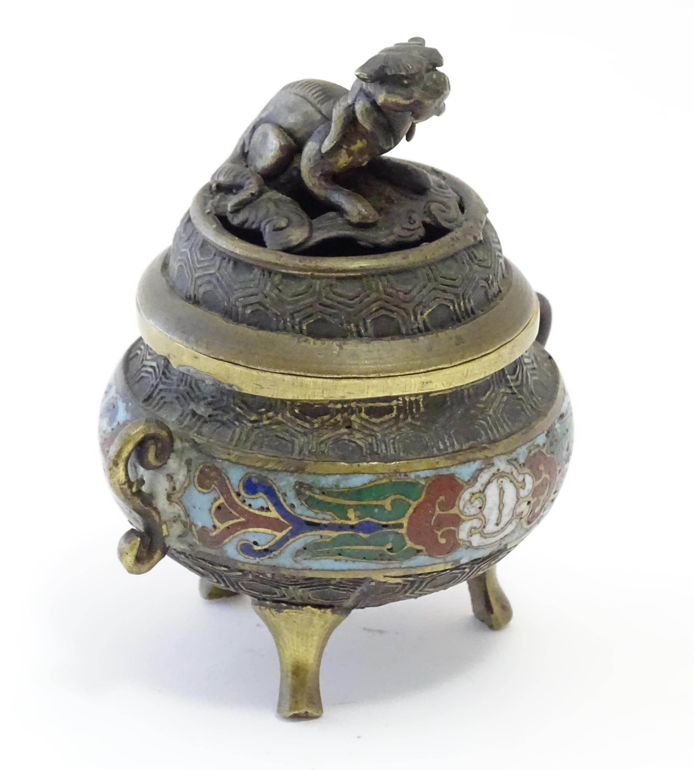 A Chinese cast brass three footed lidded censer, the body with twin handles and banded enamel