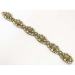 A gilt metal bracelet with filigree and enamel detail and set with green paste stones. Approx. 7 3/