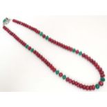 A silver necklace set with various facet cut ruby and emerald beads. Approx. 18" long Please