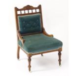 A late 19thC nursing chair with a carved cresting rail above turned finials and a deep buttoned
