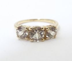 A 9ct gold ring set with a trio of yellow (csarite) stones. Ring size approx. L Please Note - we