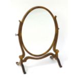 An early / mid 19thC mahogany toilet mirror with shaped supports flanking an oval mirror to the