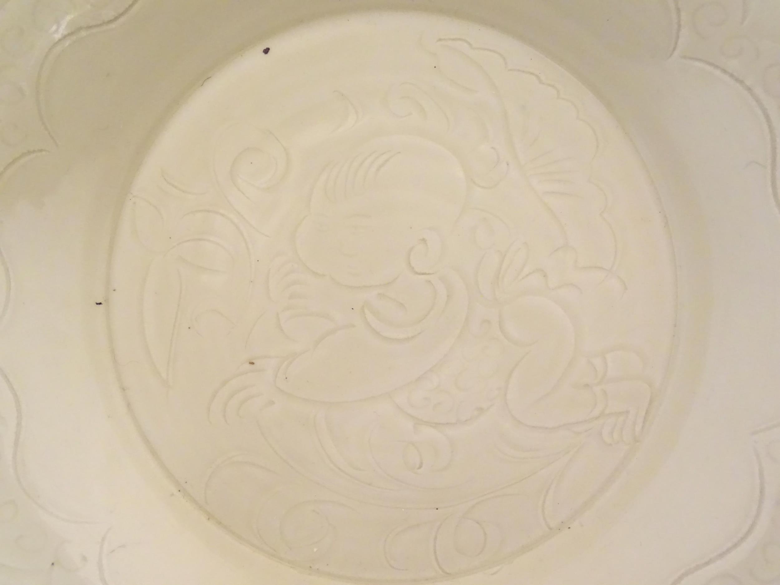 A Chinese Ding style dished plate with relief decoration depicting a stylised baby. Approx. 8" - Image 3 of 6