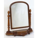 A Victorian mahogany toilet mirror with an arched top and moulded surround flanked by fluted