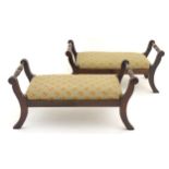 A pair of mahogany footstools with turned rails to either side, drop in seats and raised on sabre