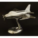 A polished steel desk model of a mid 20thC swept-wing propeller aeroplane, the support with dished