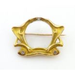 A Continental Art Nouveau gold brooch with central glazed locket section bordered by scrolling
