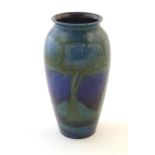 An Art Nouveau Moorcroft vase in the pattern Moonlit Blue decorated with trees in a landscape with