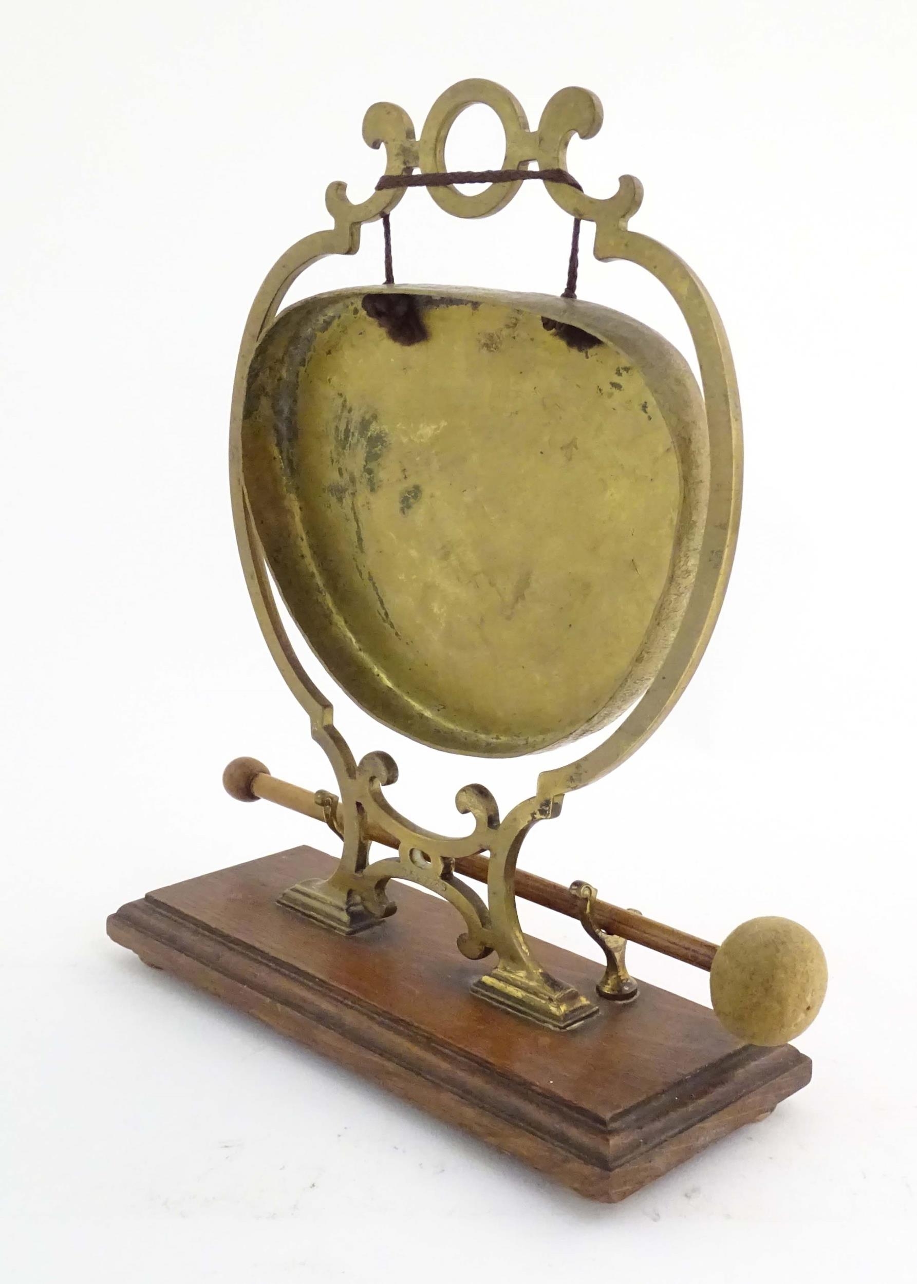 A 20thC brass table gong within a scrolling brass surround, on a rectangular oak base with beater. - Image 6 of 8