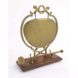 A 20thC brass table gong within a scrolling brass surround, on a rectangular oak base with beater.