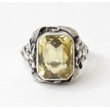 A silver ring with floral and foliate detail to shoulders set with central citrine. Ring size