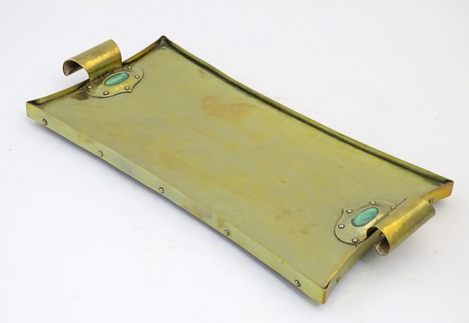 An Arts & Crafts brass tray with twin scroll handles and Ruskin style cabochon and rivet detail.