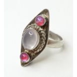 A silver ring set with central moonstone cabochon flanked by pink cabochon. Ring size approx. L