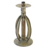 An Arts and Crafts copper and brass candlestick with a hammered finish and bowed strapwork supports,