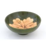 A small Moorcroft dish with hibiscus decoration. Marked under. Approx. 1 3/4" high x 4 1/2" diameter