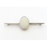 A 9ct white gold bar brooch set with central oval opal cabochon. The opal approx. 3/4" long, the