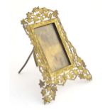 A Victorian brass easel back photograph frame, the surround with scrolling vine leaves. Approx. 7"