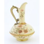 A Royal Worcester jug / ewer with a cream ground, floral decoration and gilt highlights. Marked