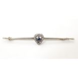 A 9ct white gold bar brooch set with blue stone bordered by white stones in a heart setting. The