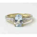 A 9ct gold ring set with central oval facet cut aquamarine flanked by three diamonds to each