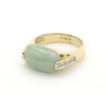 A 9ct gold ring set with pale jade cabochon flanked four diamonds to each shoulder. Ring size