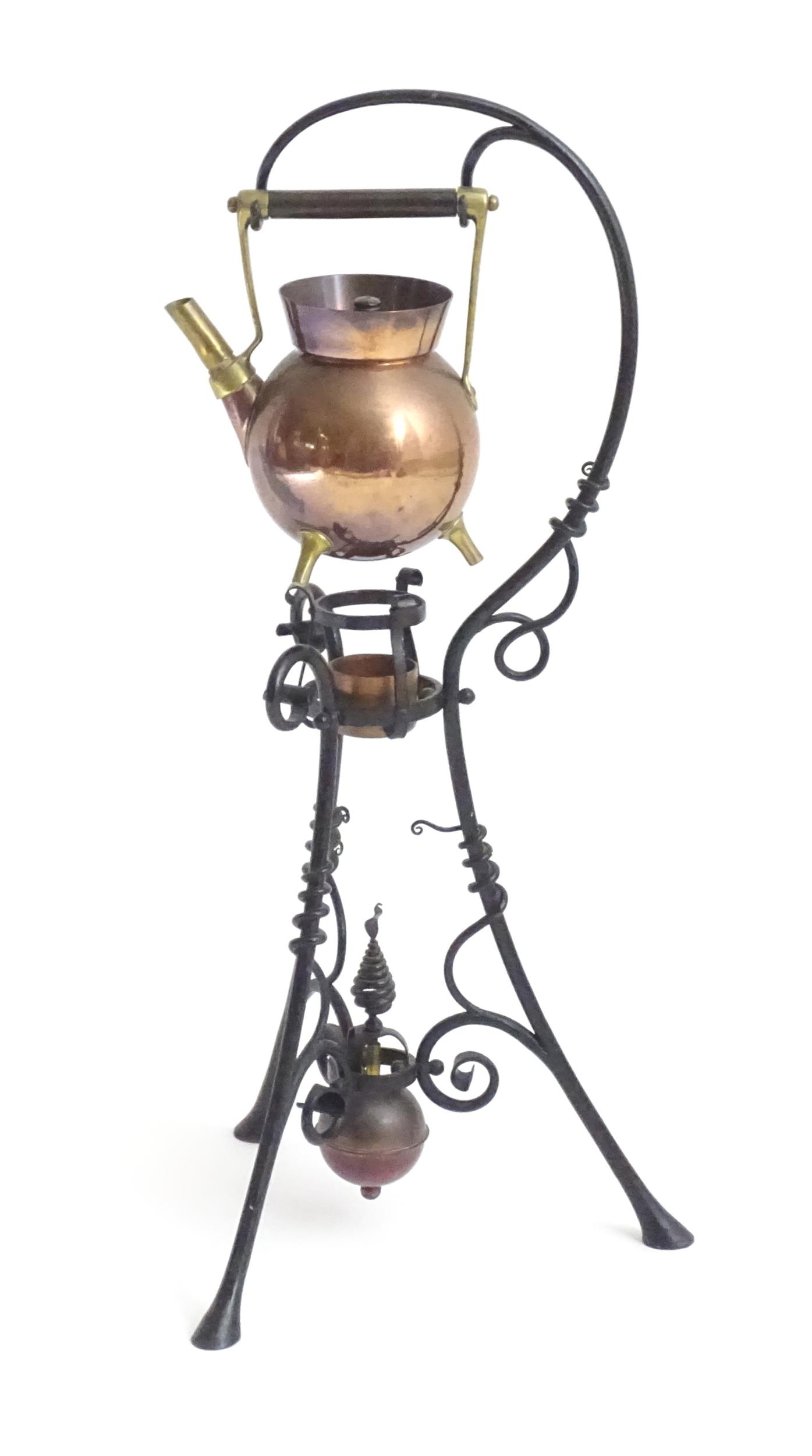 An Arts & Crafts copper and brass spirit kettle on a scrolling wrought iron stand designed by Dr