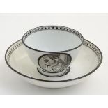 A 19thC tea bowl and saucer, decorated with monochrome roundels depicting a seated man warming by