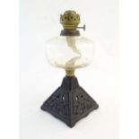 An early 20thC Falk's oil lamp, the clear glass reservoir supported by a cast iron pyramid base with