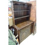 An early 20thC dresser, the plate rack with two shelves, the base with two drawers over two