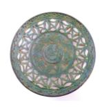A Spanish terracotta Gongora Ubeda charger with a green glaze, pierced decoration and stylised
