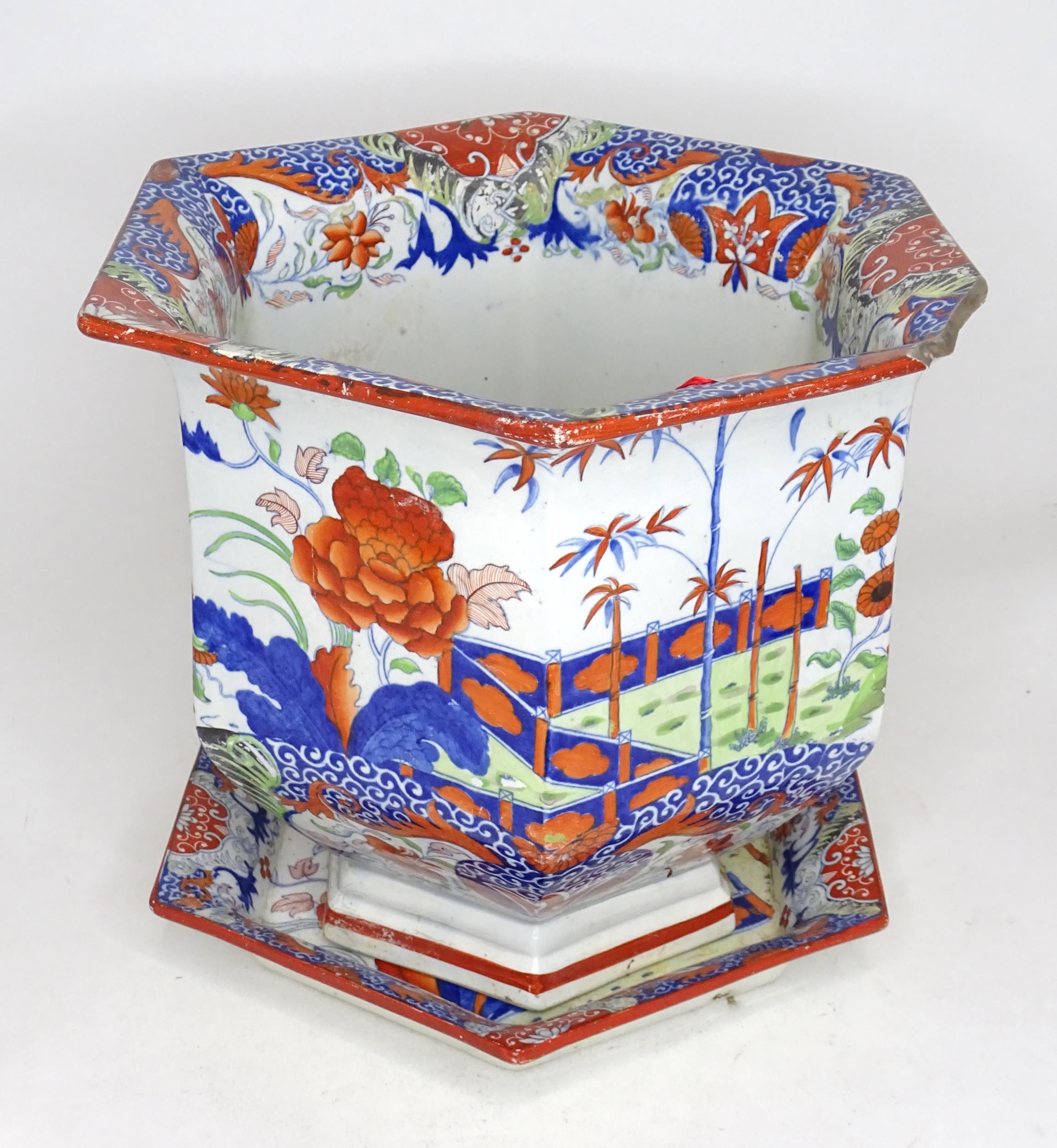 A hexagonal jardiniere / planter and stand with Chinese style decoration with flowers and foliage.