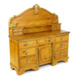 A Victorian pine dresser with a shaped carved upstand above two opposing sets of small drawers,