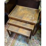 A mid 20thC English nest of three tables, each constructed from teak with inset tile tops and