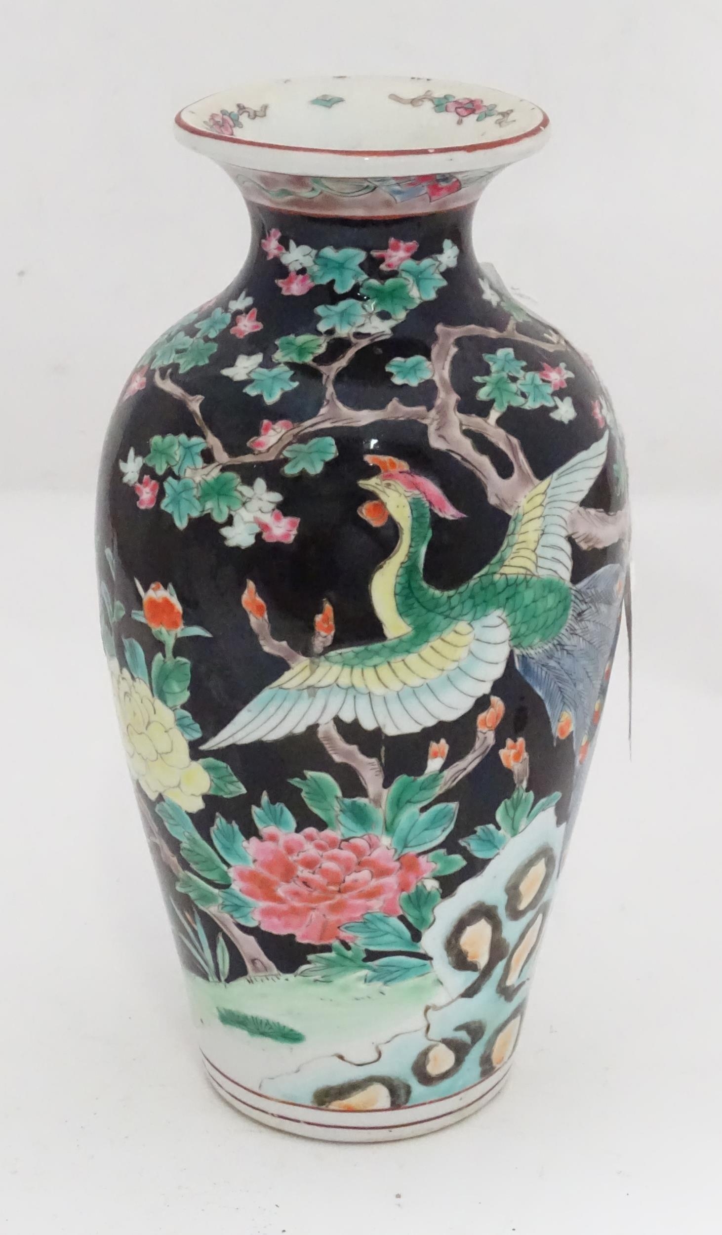 An Oriental vase decorated with a peacock in a landscape with flowers. Approx. 9 3/4" high Please