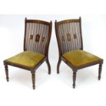 A pair of early 20thC slipper chairs, mounted by turned finials above shaped slatted backrests,