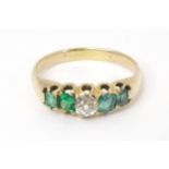 An 18ct gold ring set with central diamond flanked by two emeralds. Ring size approx R Please Note -