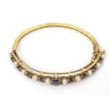 A 9ct gold bangle bracelet set with garnets and seed pearls with garnets and pearls Please Note - we