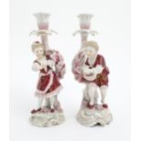 Two Continental porcelain figural candlesticks with stylised floral sconces, one stem depicting a