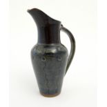 A studio pottery jug by Jennie Gilbert with banded fish detail to shoulder and relief roundel