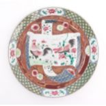 A Chinese plate decorated with a scrolling central panel depicting two cockerels / roosters