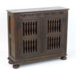 A late 19thC ventilated oak livery cupboard, the cabinet having a carved frieze and gadrooned