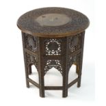 A late 19thC folding table with a circular top having intricate carved detailing and inlaid brass