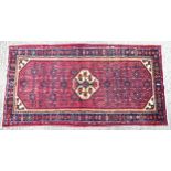 Carpet / rug : A Malayer rug having red ground with repeated geometric motifs bordered by bands of
