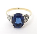 A 9ct gold ring set with blue coloured paste stone to centre with white paste stones to shoulders in